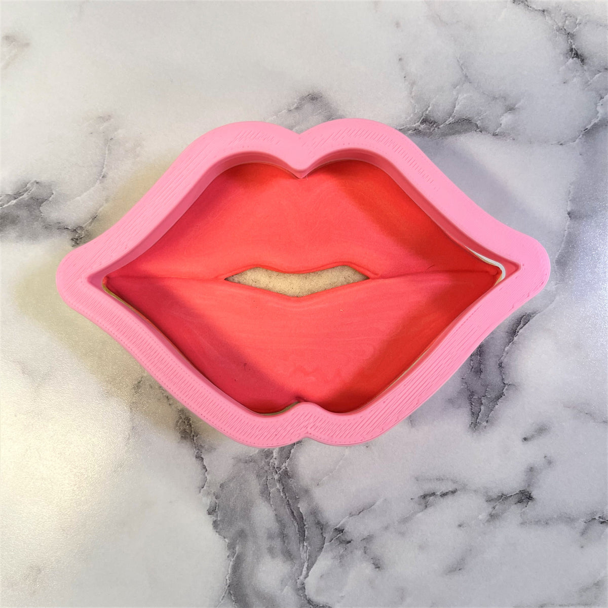 Pink silicone puckered lips cookie cutter with red interior and beige center for baking and crafting