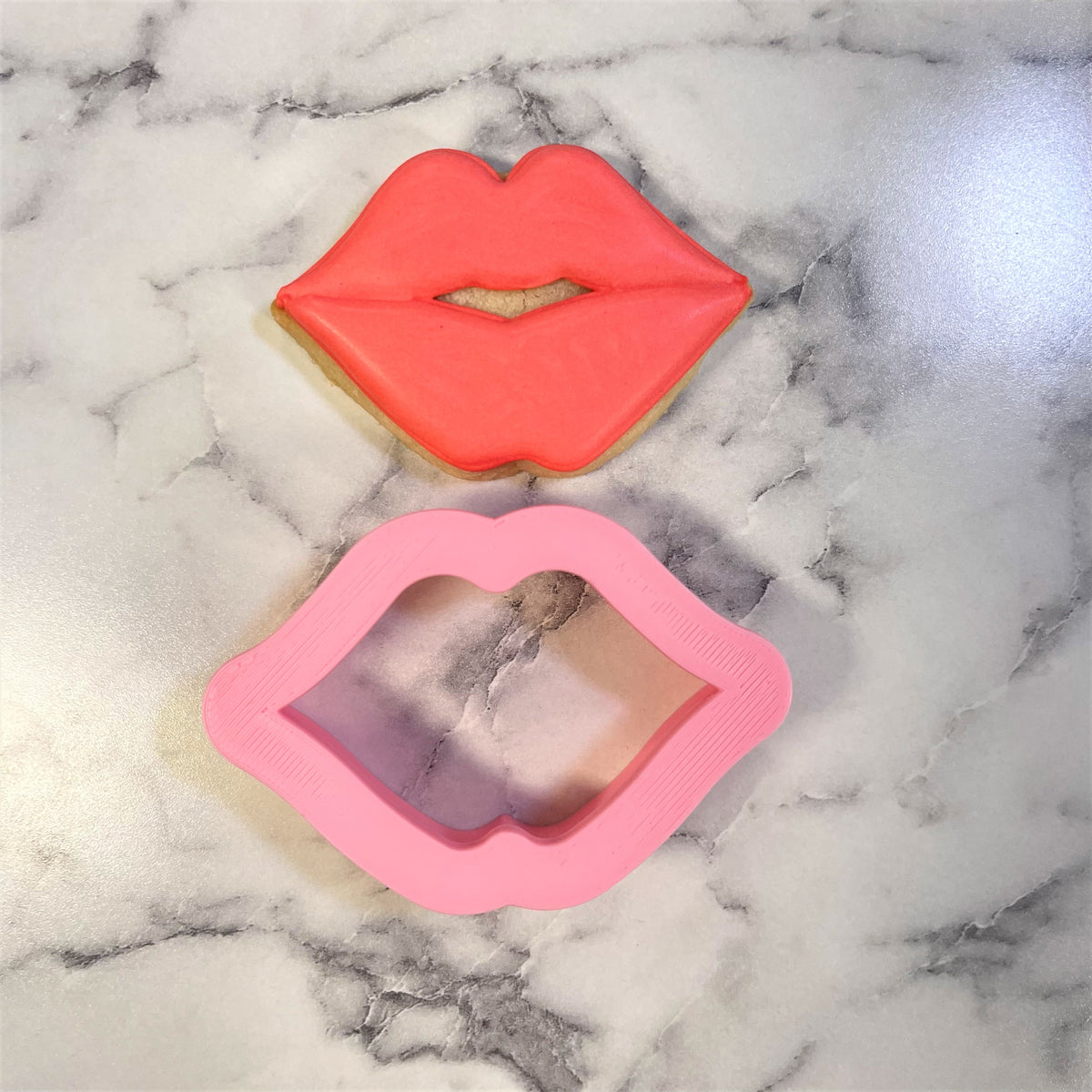 Mini puckered lips cookie cutter pink silicone lip-shaped cutter with matching red frosted cookie beside it