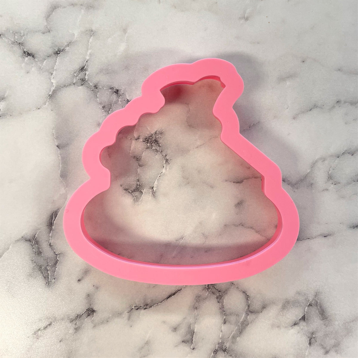 Pink silicone poop-shaped mold containing a white and gray marbled object for pumpkin pie on plate cookie cutter