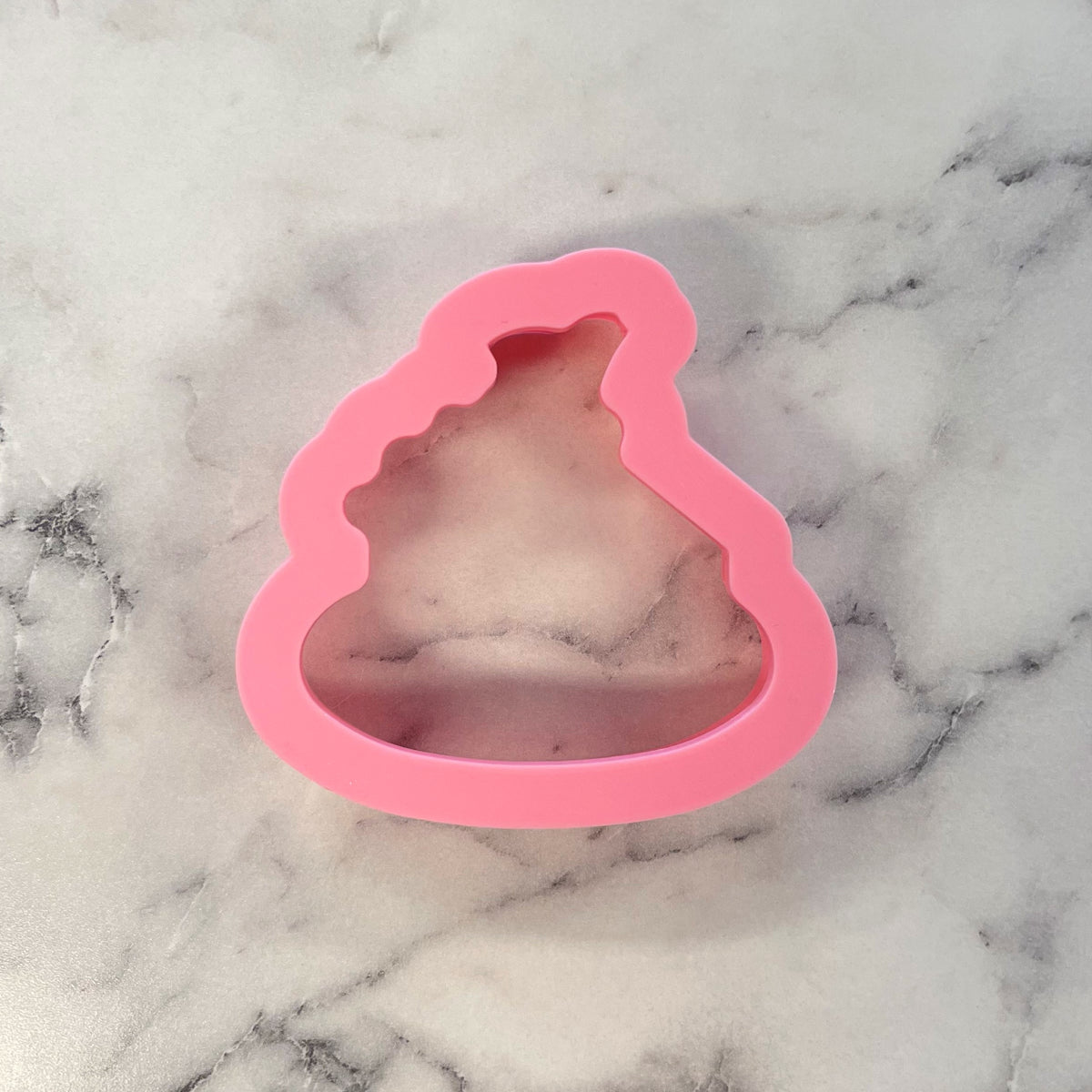 Pink silicone poop emoji cookie cutter for mini pumpkin pie shaped cookies on a plate