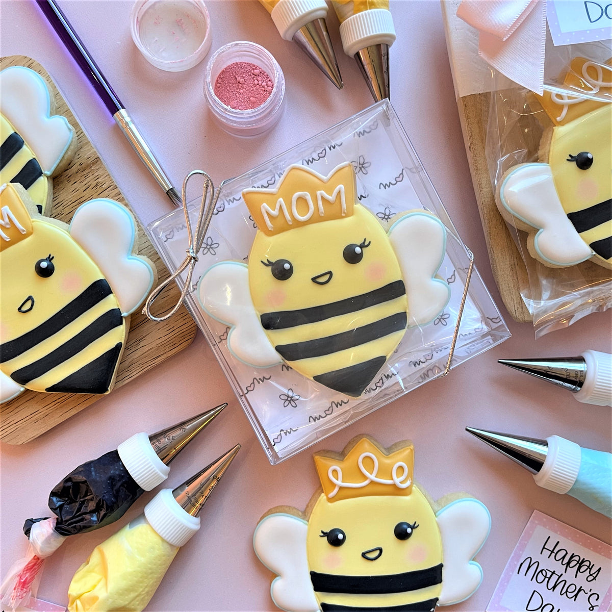Yellow and black bee shaped cookie with a white mom crown and pink cheeks made using queen bee cookie cutter