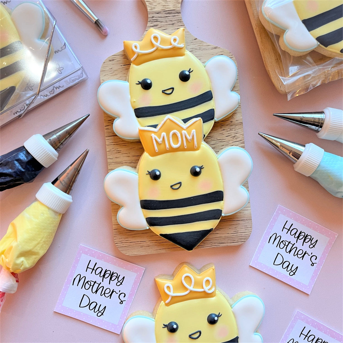Yellow and black bee-shaped cookies with white wings and yellow crowns made with queen bee cookie cutter designed as mother and child