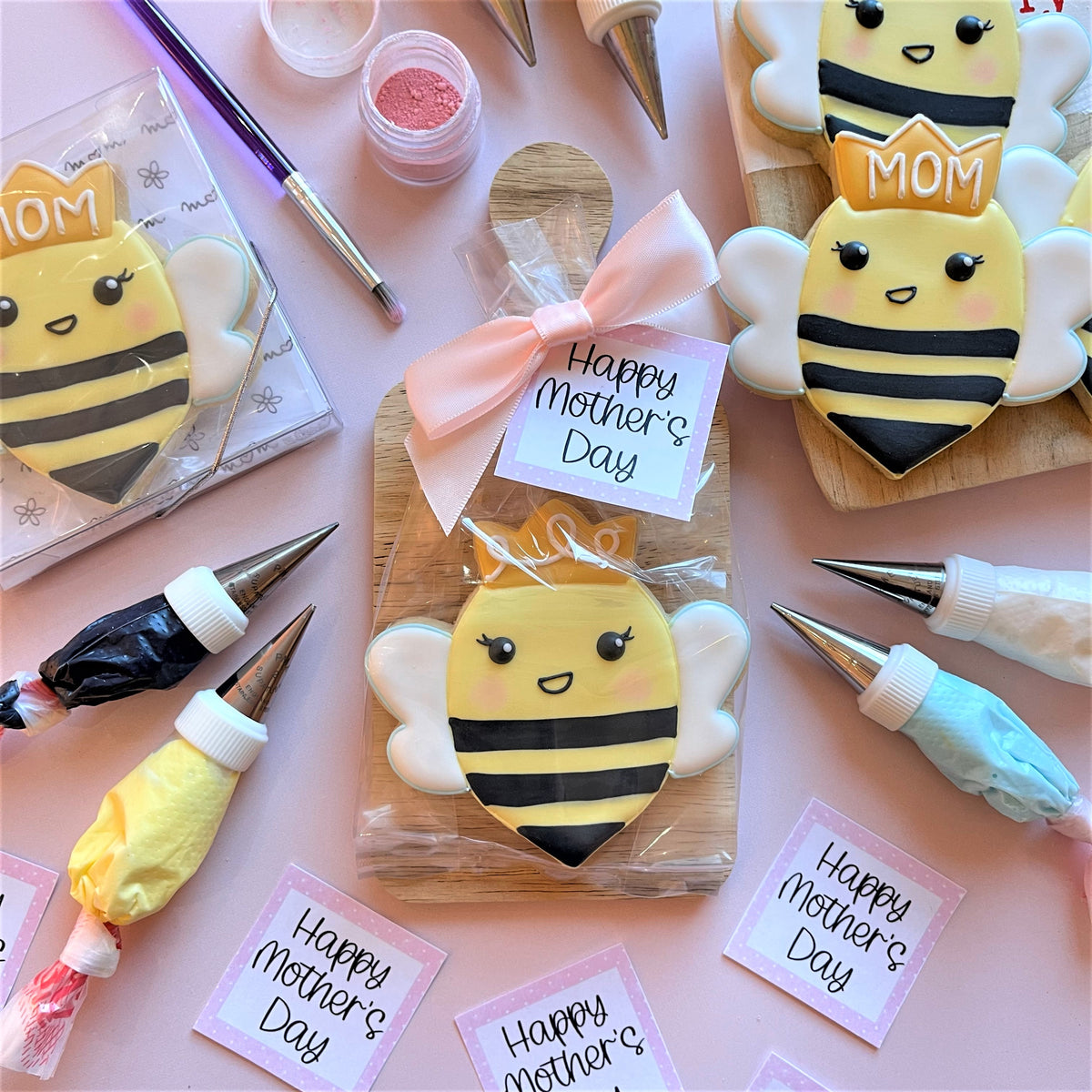 Yellow and black bee-shaped sugar cookie with white icing wings and mom text made using queen bee cookie cutter