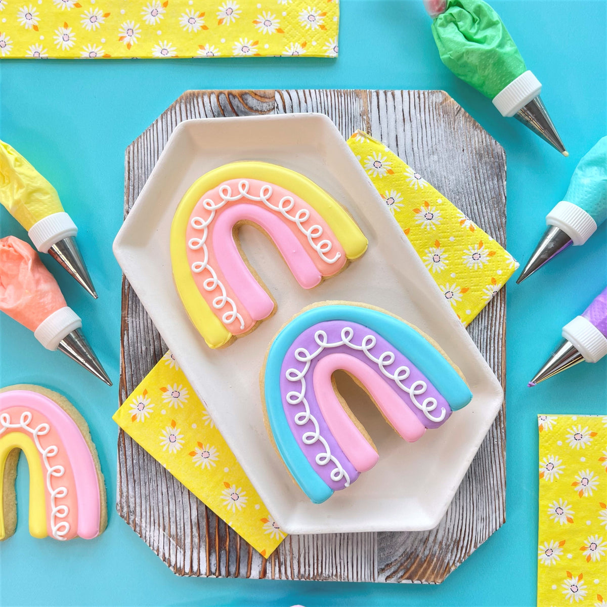 Pastel rainbow-shaped sugar cookies with smooth icing and delicate white piped details from spring showers to flowers cookie decorating class recording
