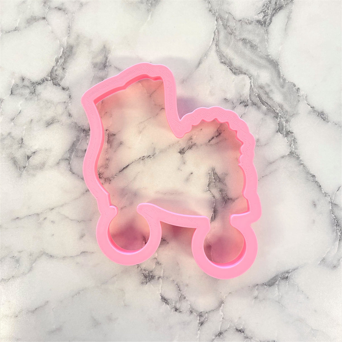 Pink plastic baby carriage cookie cutter shaped like a roller skate with pom pom for baking and decorating