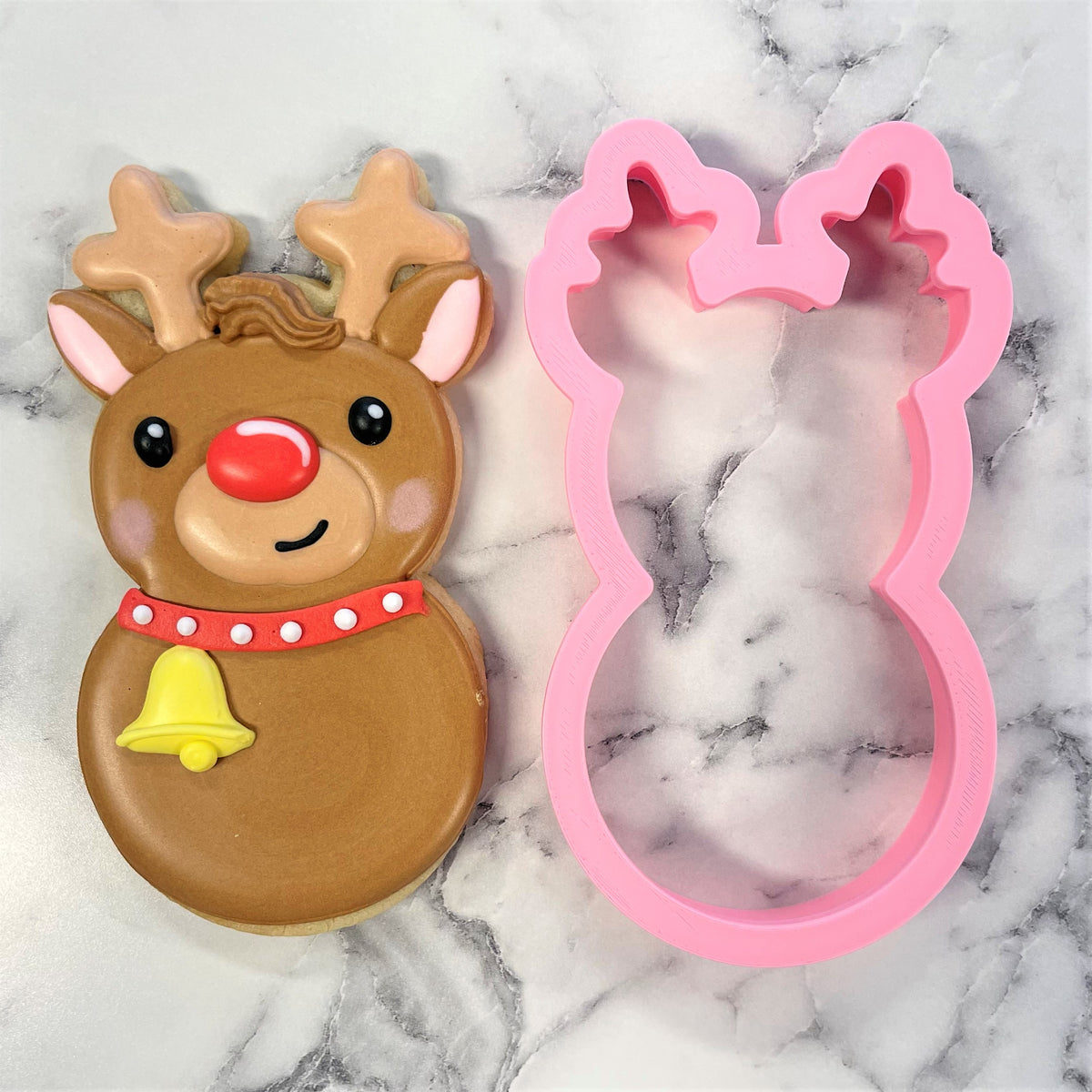 A pink silicone reindeer roly poly cookie cutter with detailed antlers and a smiling face design
