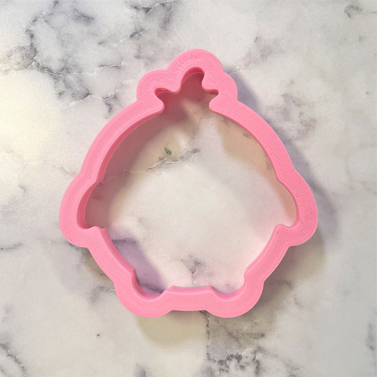 Pink plastic round chick cookie cutter shaped like a princess dress for baking and crafting use