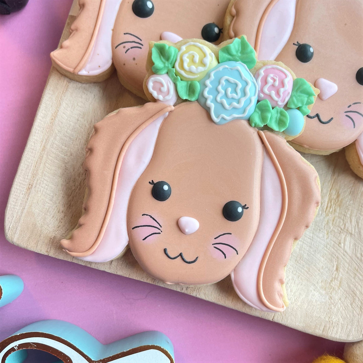 Pastel peach-colored bunny cookie with long ears black button eyes pink nose and floral icing crown for rustic easter class
