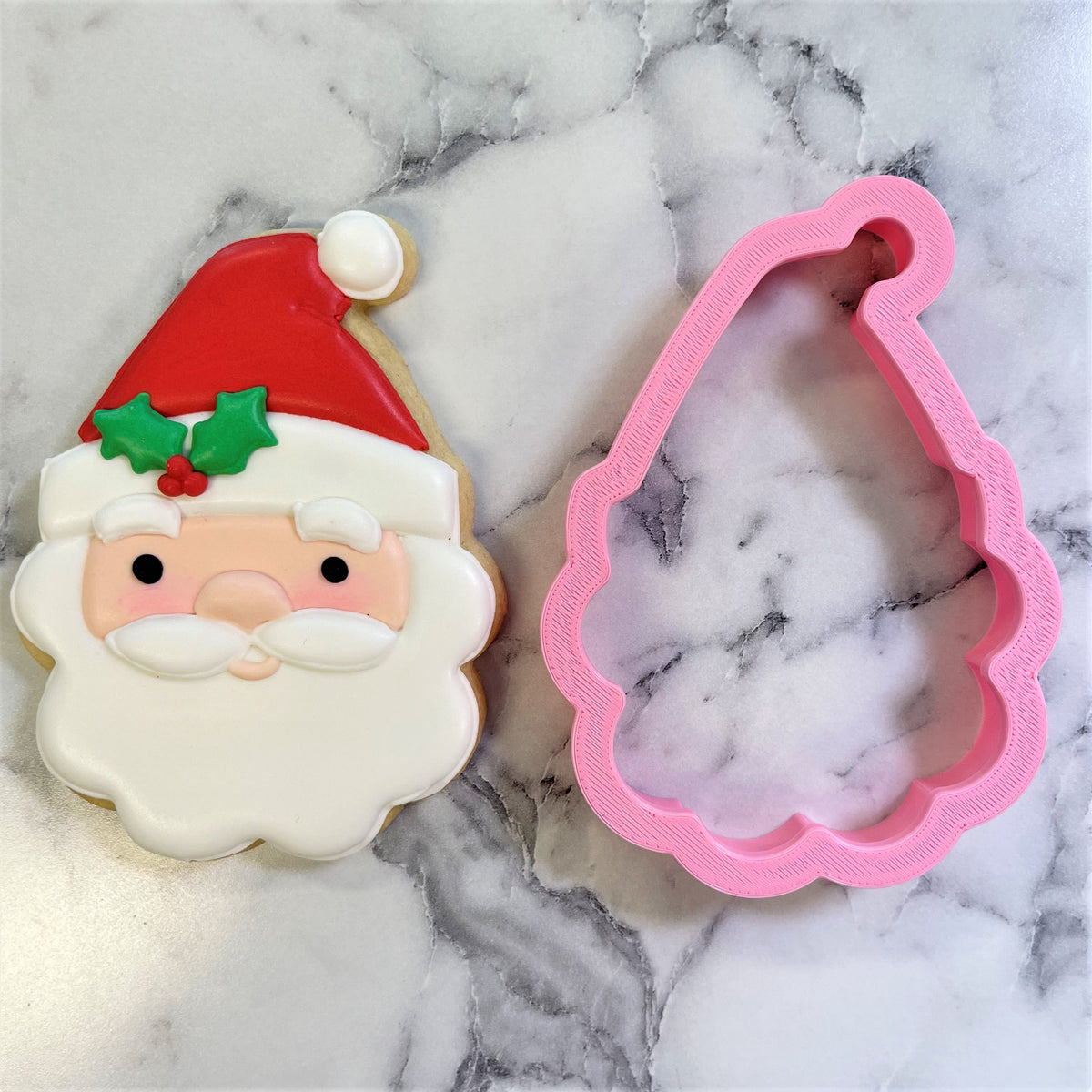 A pink plastic classic santa cookie cutter with scalloped edge and textured surface for festive baking