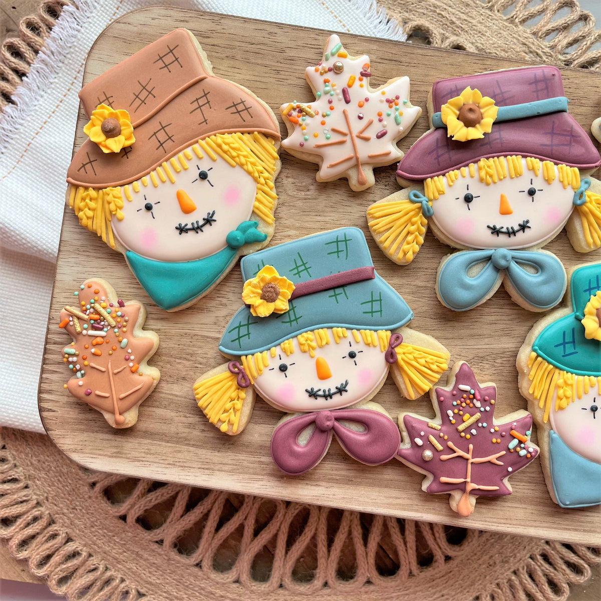 Delicate scarecrow girl face sugar cookies decorated with vibrant brown blue purple teal yellow and pink icing