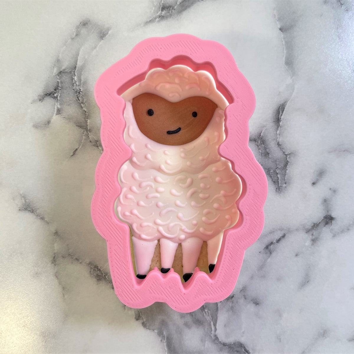 Pink silicone sheep cookie cutter with textured wool details and a smiling face for baking and crafting