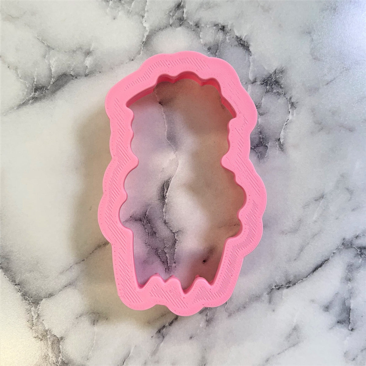 Pink silicone sheep cookie cutter mold with scalloped edges and textured interior for soap or candle making