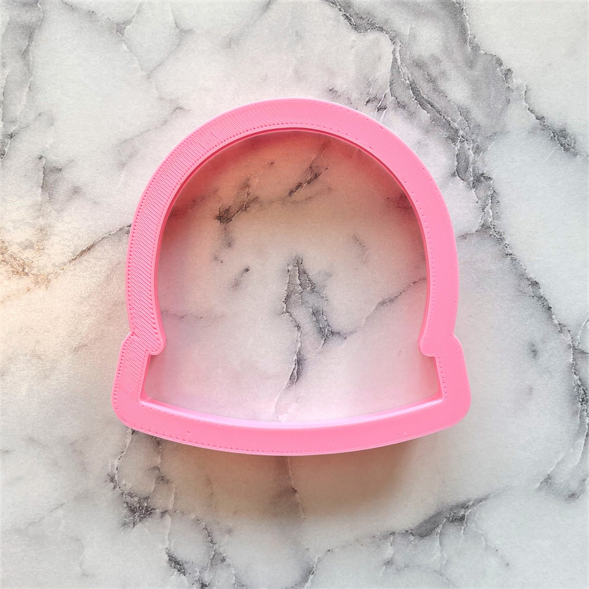 Pink plastic snow globe dome cookie cutter shaped like a helmet for festive baking and cookie shaping