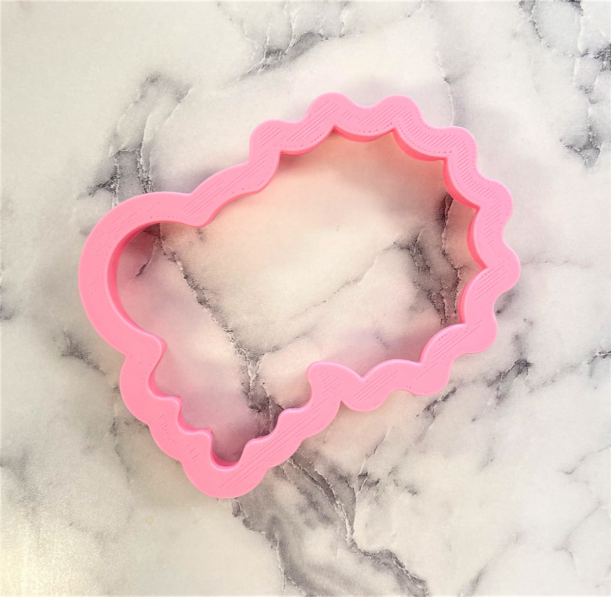 Pink cloud-shaped metal cookie cutter with scalloped edge from sun and cloud cookie cutter set