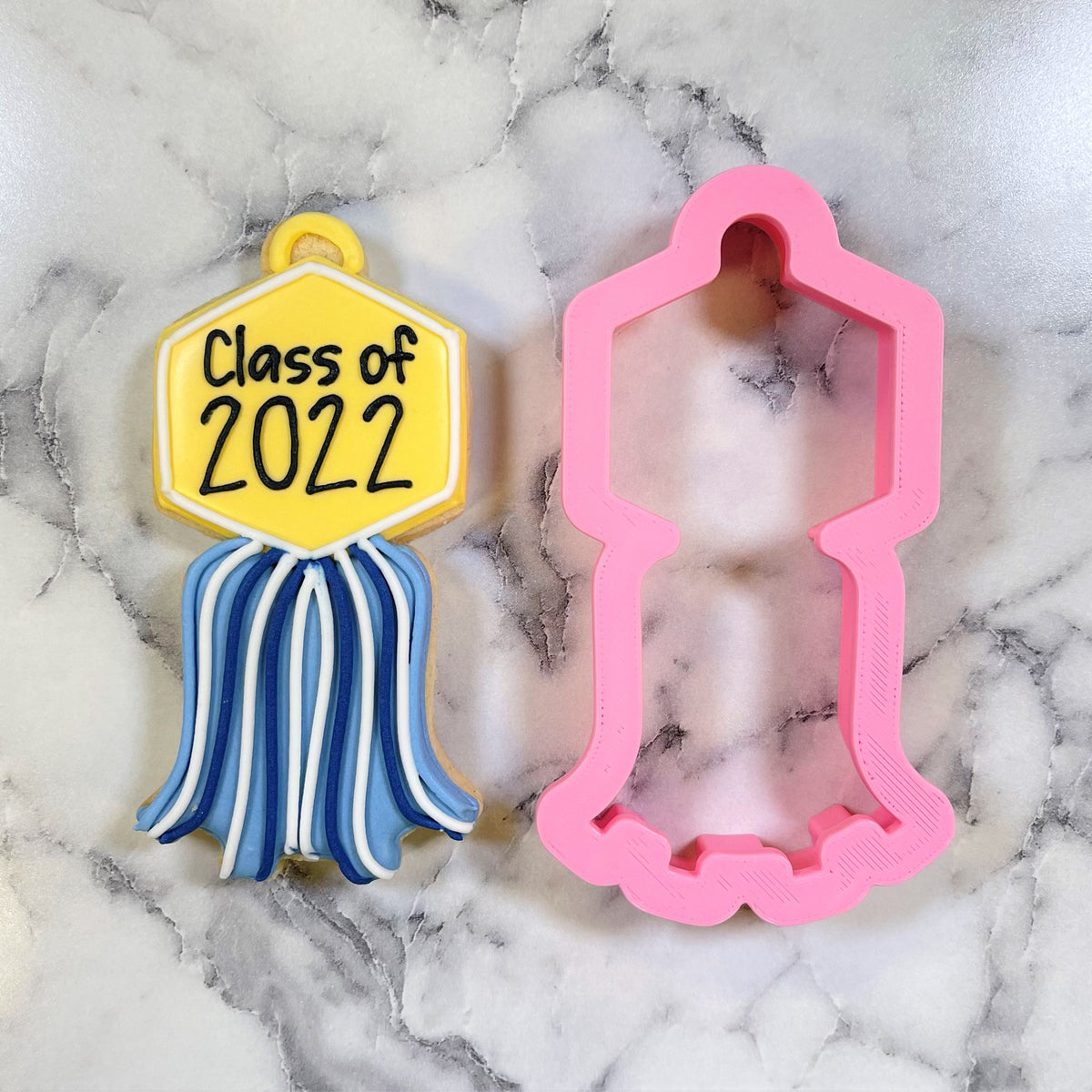 Tassel plaque cookie cutter with a pink silicone mold and a yellow and blue class of 2022 graduation ribbon cookie