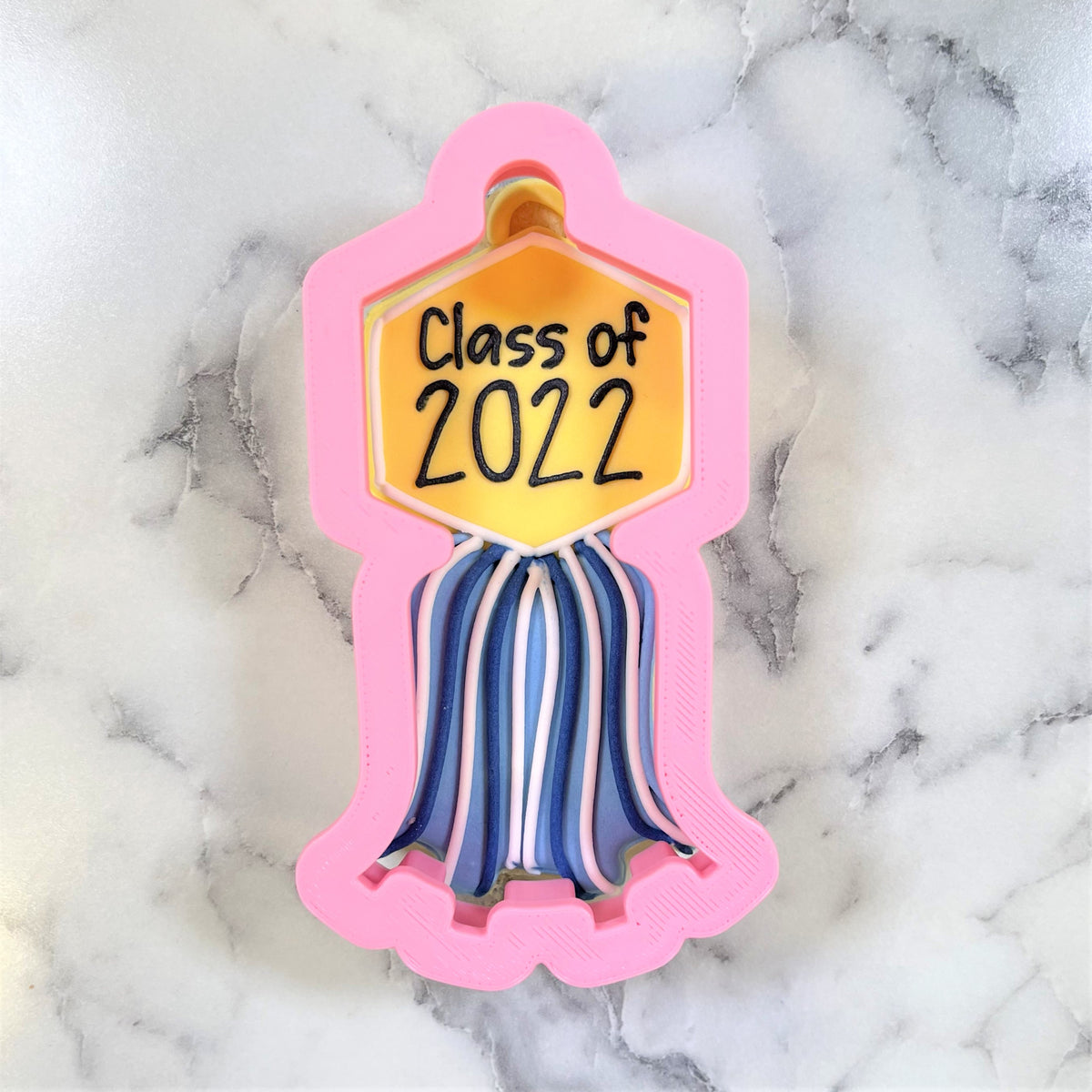Pink 3d-printed tassel plaque cookie cutter with yellow class of 2022 hexagonal plaque and striped tassel details