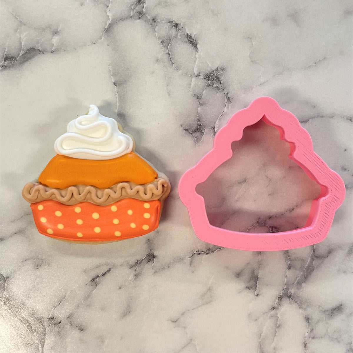 Mini thanksgiving pie cookie cutter pink silicone next to decorated orange pumpkin pie sugar cookie