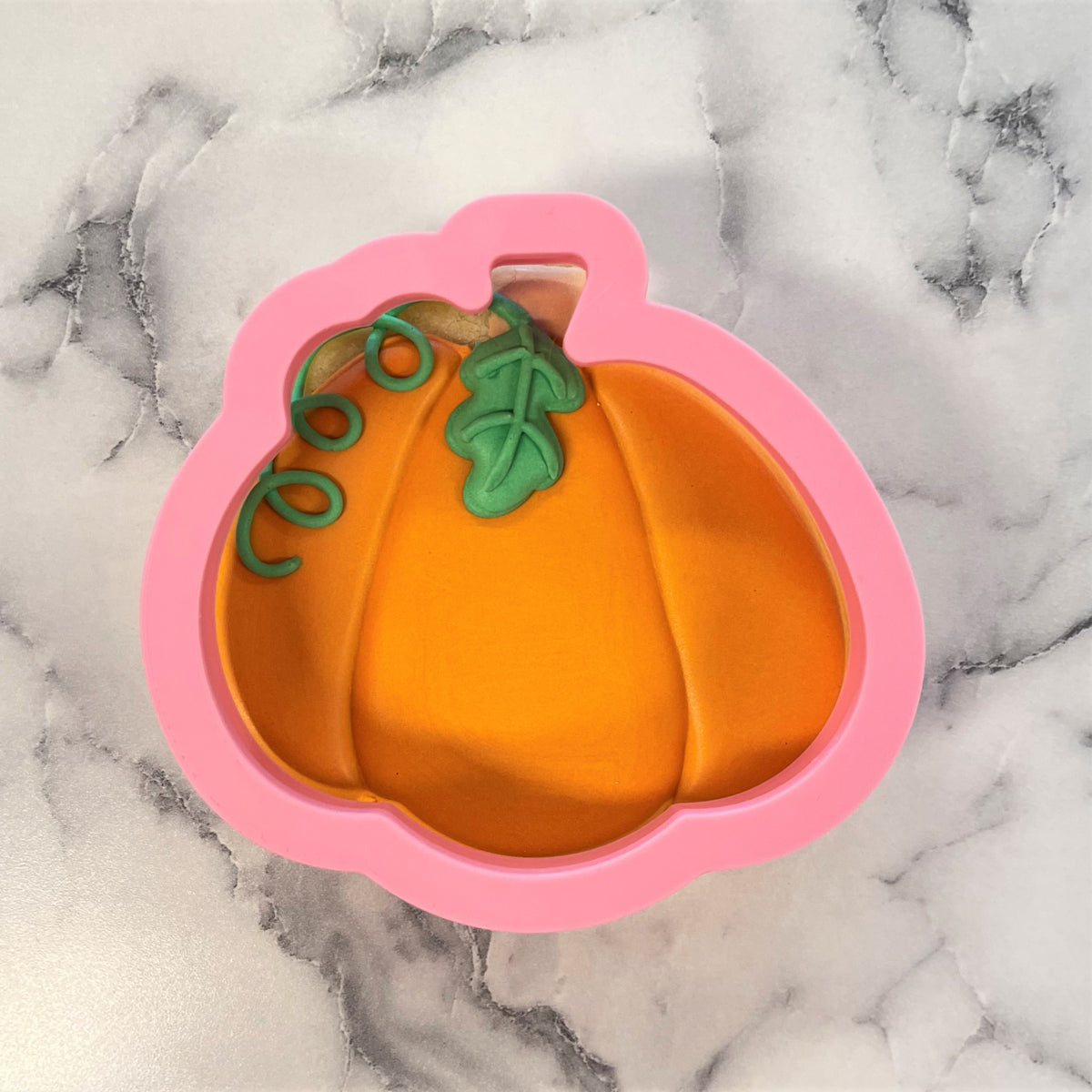 Pink silicone pumpkin-shaped baking mold with orange and green details for thanksgiving pumpkin cookie cutter