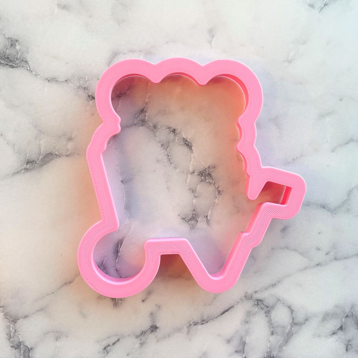 Pink plastic cookie cutter shaped like a bear from the wheelbarrow with flowers cookie cutter set