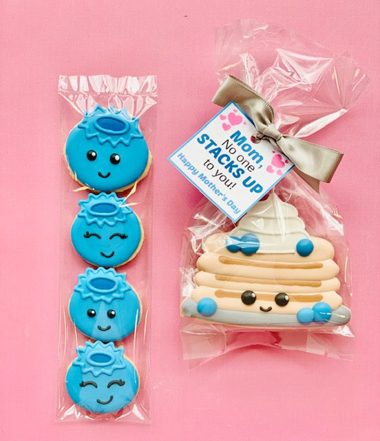 Blue smiling face cookie with halo packaged in clear plastic from pancake with blueberry cookie cutter set