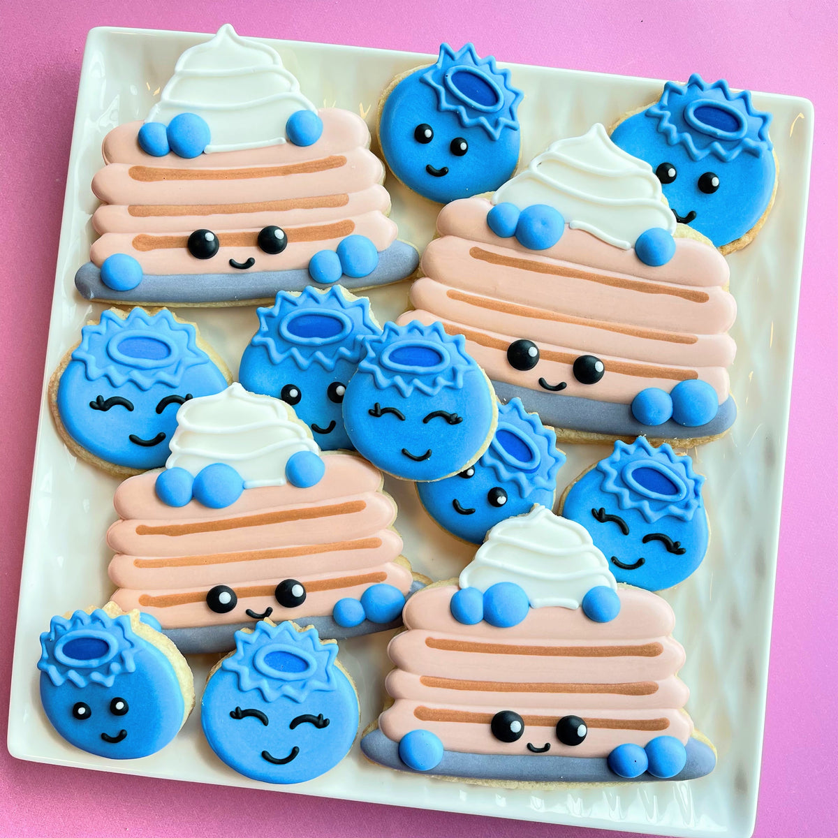 Cute blue and pink pancake-shaped cookies with white icing swirls and blueberry cookie cutter set decorations