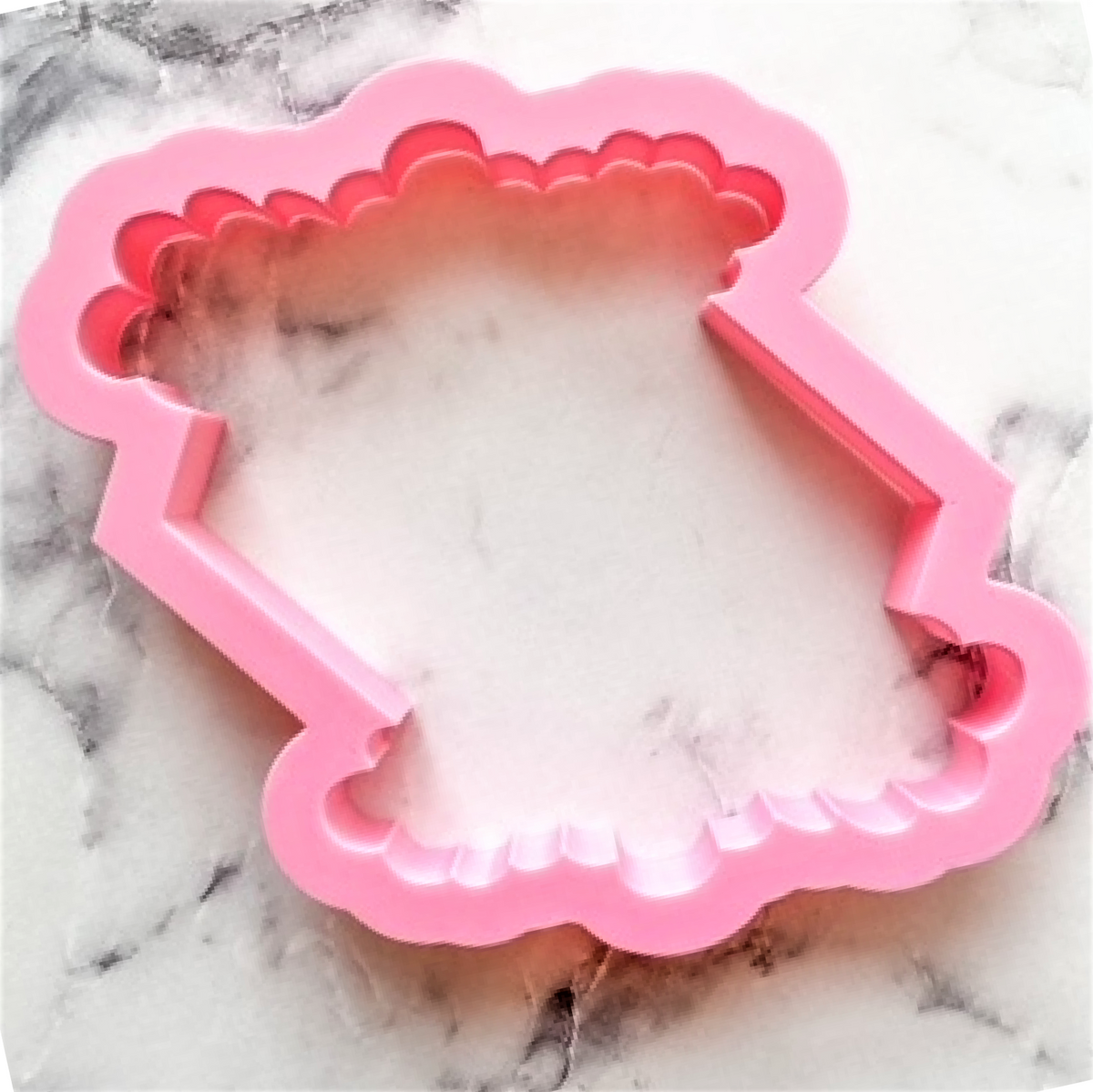 Pink silicone floral plaque cookie cutter shaped like a baby onesie with scalloped edges for baking crafts