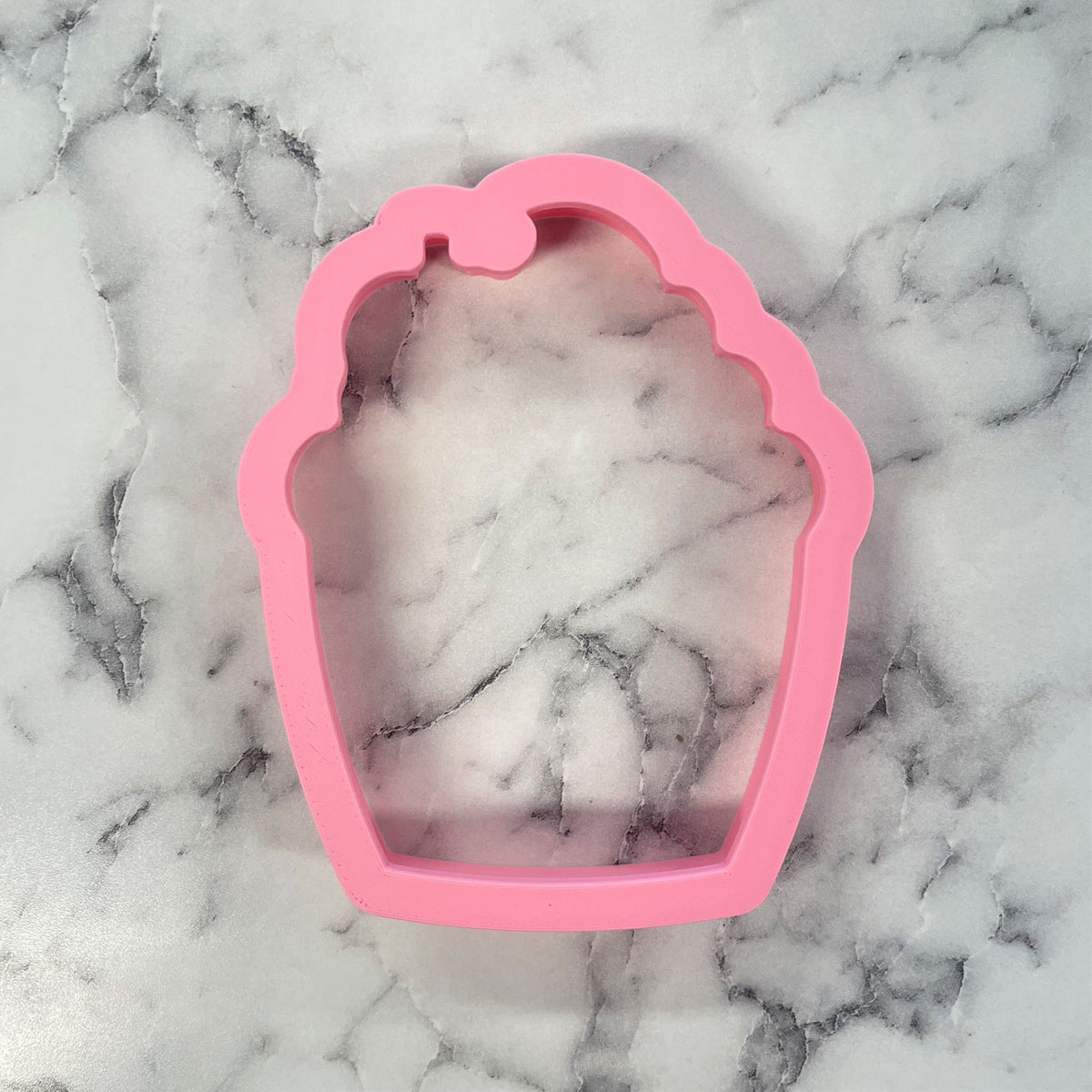 Pink silicone cupcake-shaped cookie cutter for pumpkin cupcake cookies with flexible non-stick material