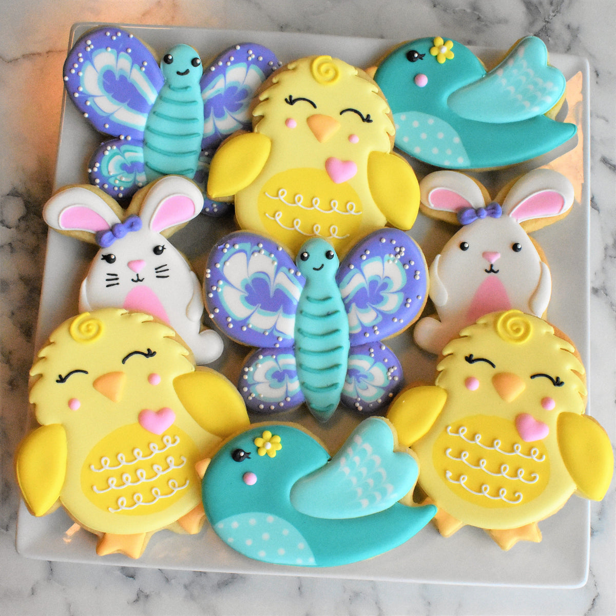 Pastel-colored sugar cookies shaped like chicks butterflies and birds with intricate icing from springtime decorating class recording