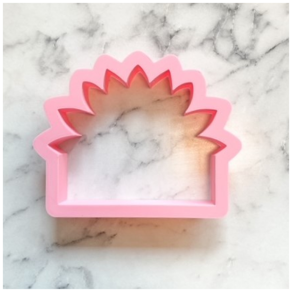 Pink plastic sunflower plaque cookie cutter with serrated edges and hollow center for decorative baking