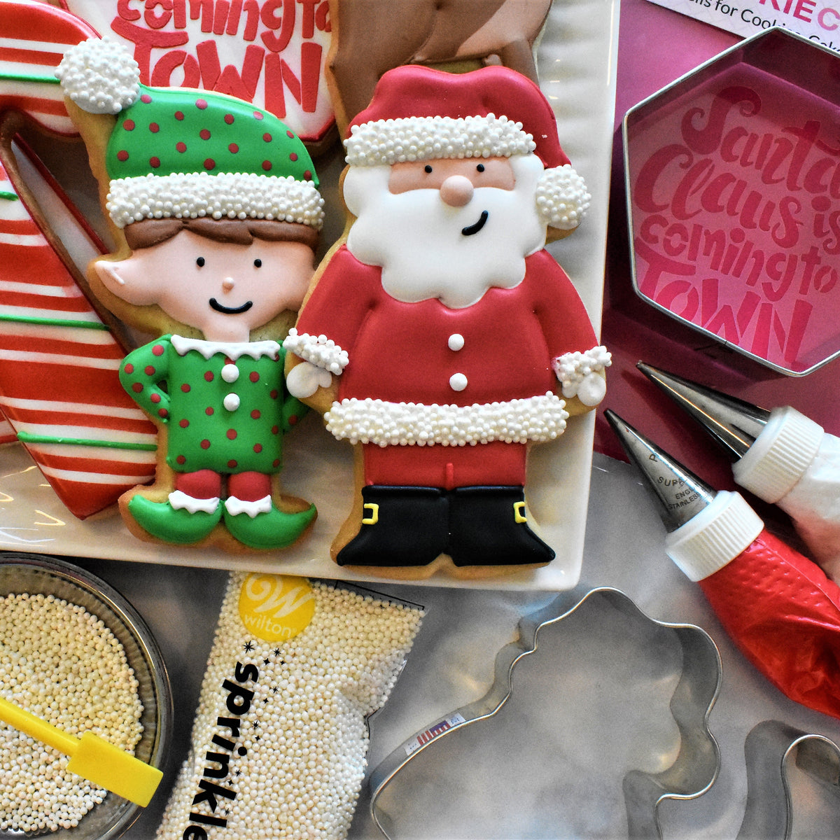 Red and white frosted santa claus cookie with green polka dotted elf cookie from santa decorating kit with piped icing details