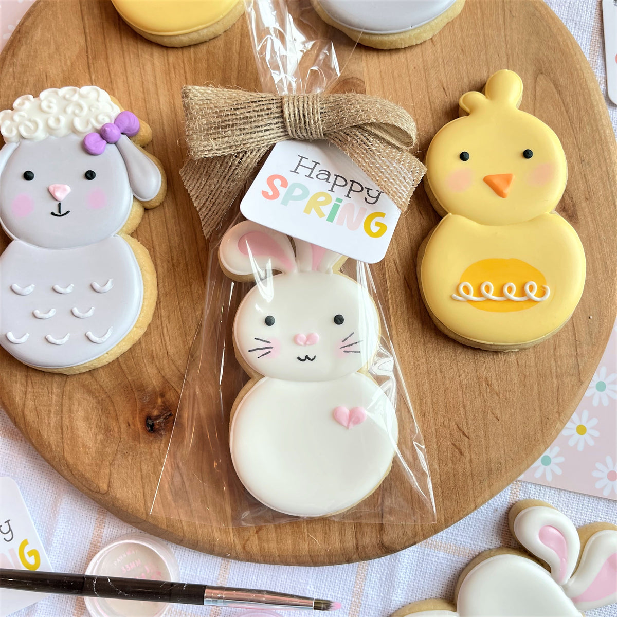 A white frosted bunny cookie with pink heart details packaged in clear cellophane with a burlap bow for roly poly flour box club