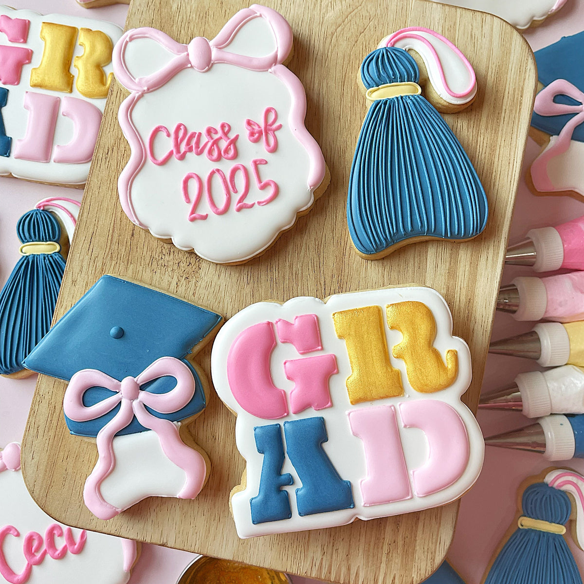 Pastel pink and blue sugar cookies shaped like graduation cap gown and girl grad made with graduate cookie cutter bundle