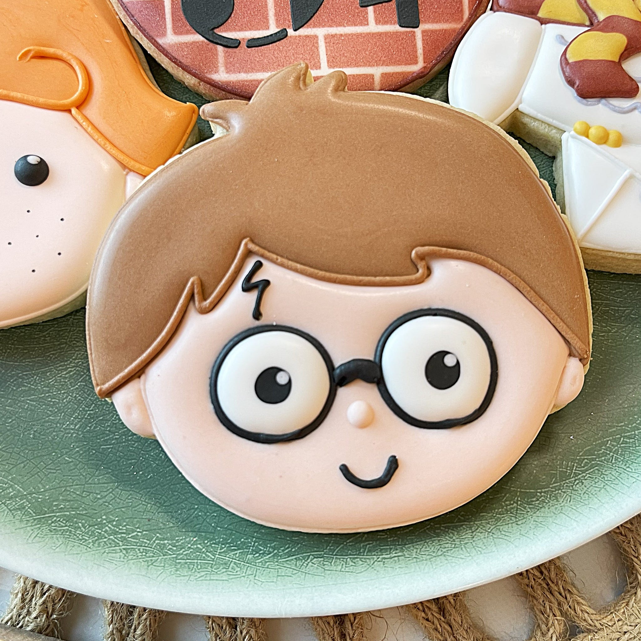 Cookie with a cartoon character face featuring glasses on a green plate.