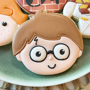 Cookie with a cartoon character face featuring glasses on a green plate.