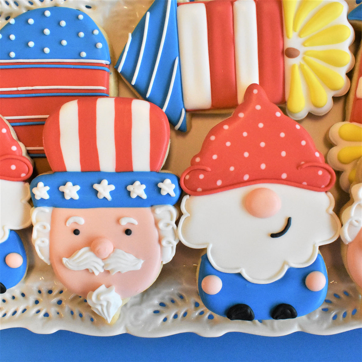 Uncle sam gnome cookie cutter shaped red and white polka-dotted gnome cookie with blue outfit pink cheeks and black shoes
