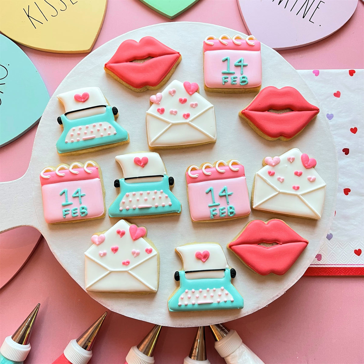 Mini envelope with hearts cookie cutter with delicate sugar cookies shaped like lips envelopes and typewriters in pastel colors