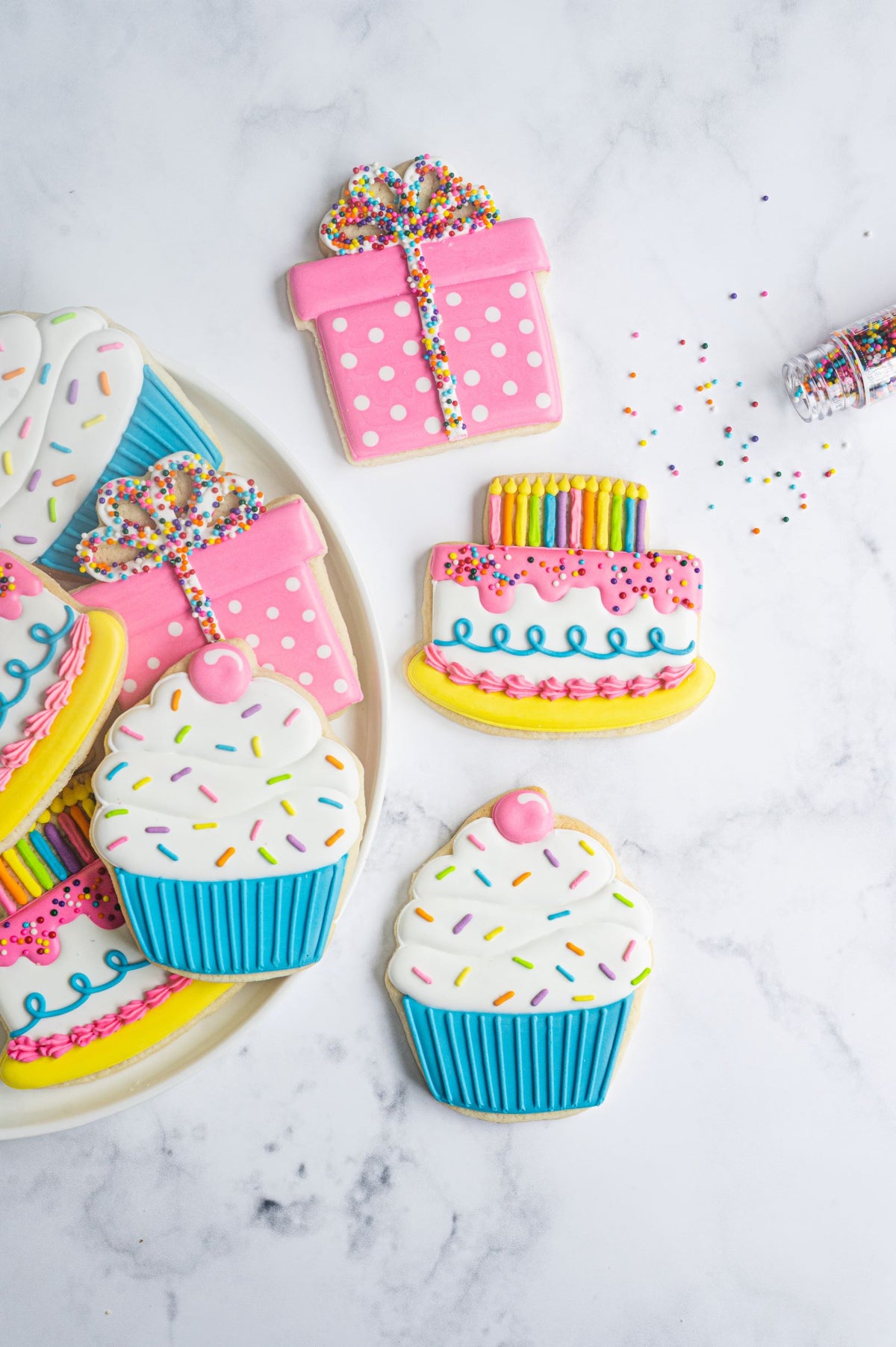 The crafted cookie by Anne Yorks is a pink polka-dotted gift box cookie with a rainbow sprinkle bow and striped ribbon