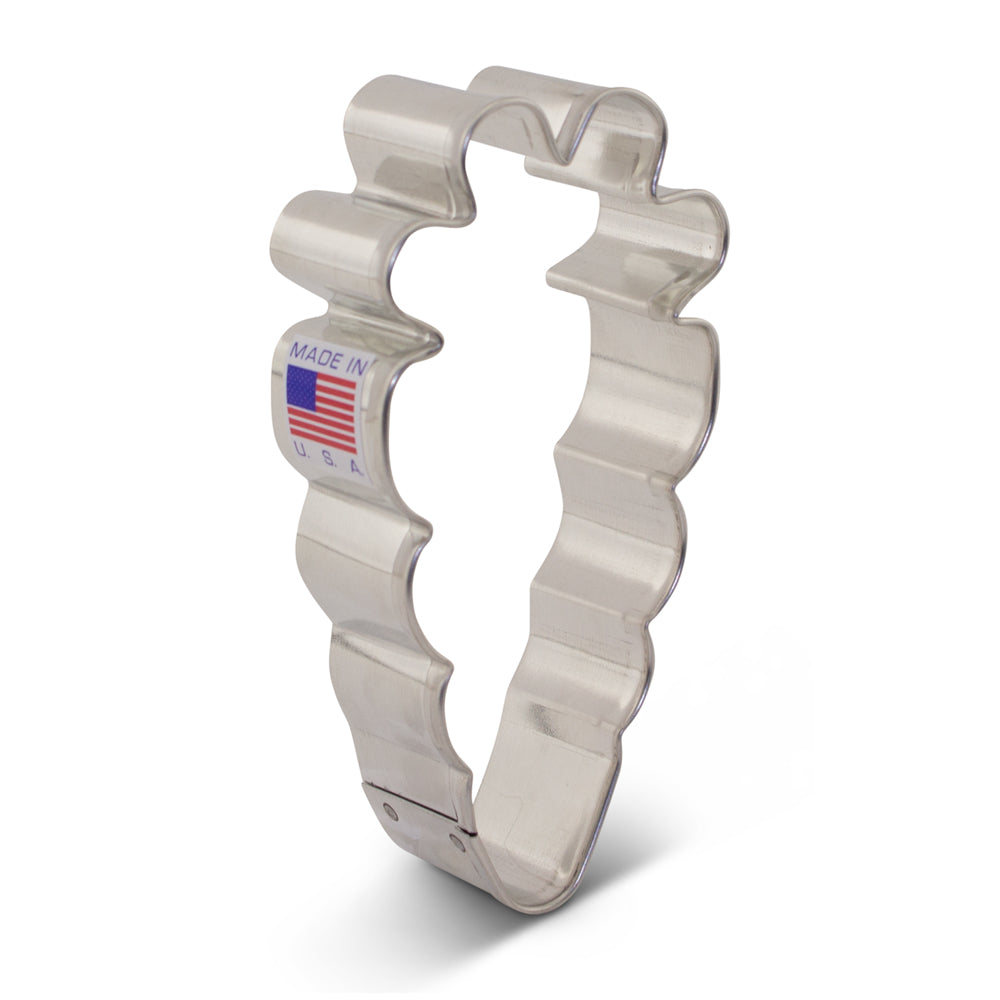 Silver metallic cookie cutter shaped like a baby bootie with scalloped edges and made in usa label for carrot cookies